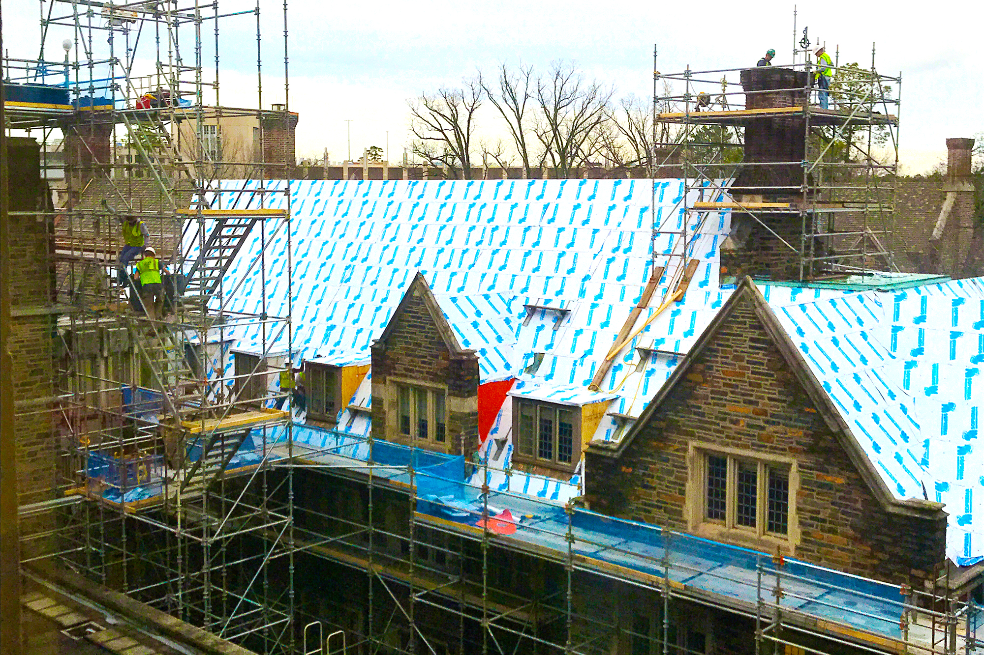 Construction workers replacing the roof of Smith Dormitory